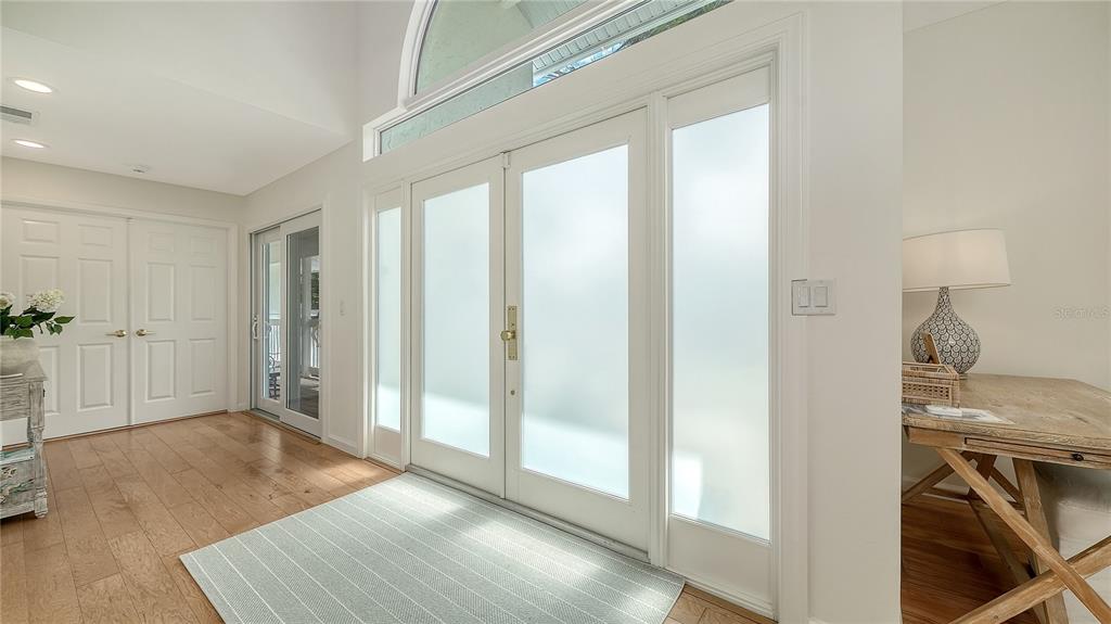 An entryway features white double doors with frosted glass panels, light wood flooring, and a rug — 476 MEADOW LARK DRIVE, SARASOTA, FL