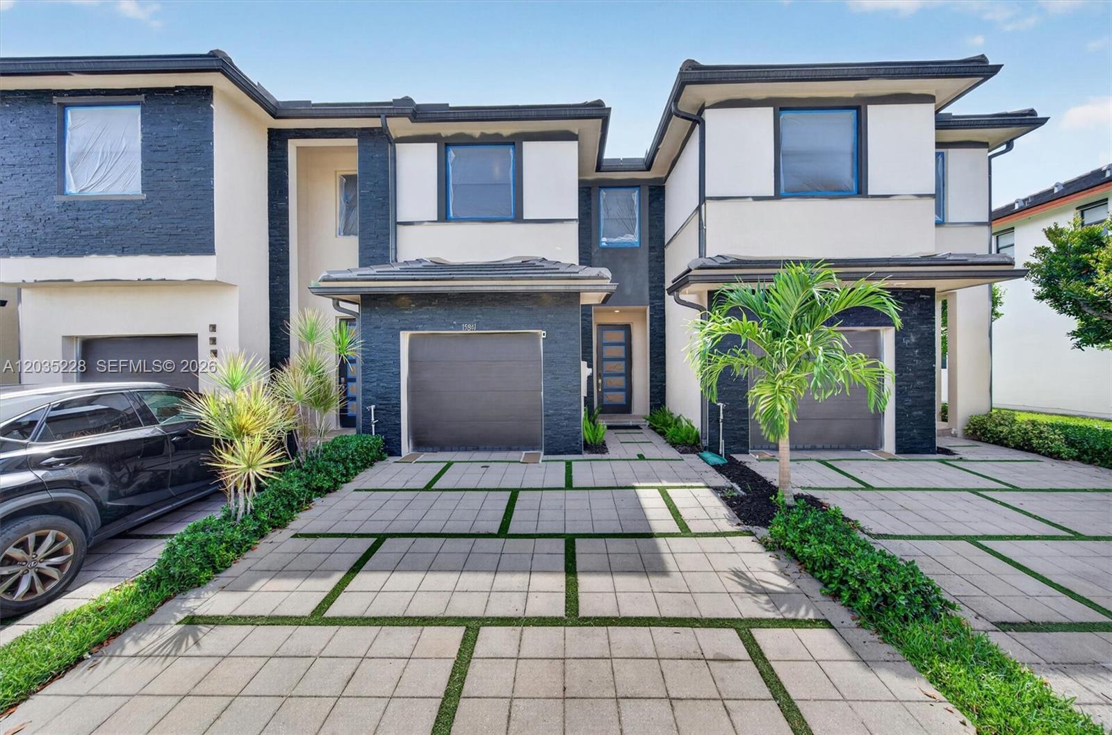The exterior features a two-story townhouse with a paved driveway, garage, and modern facade — 15841 NW 91st Ct, Miami Lakes FL 33018, MIAMI LAKES, FL