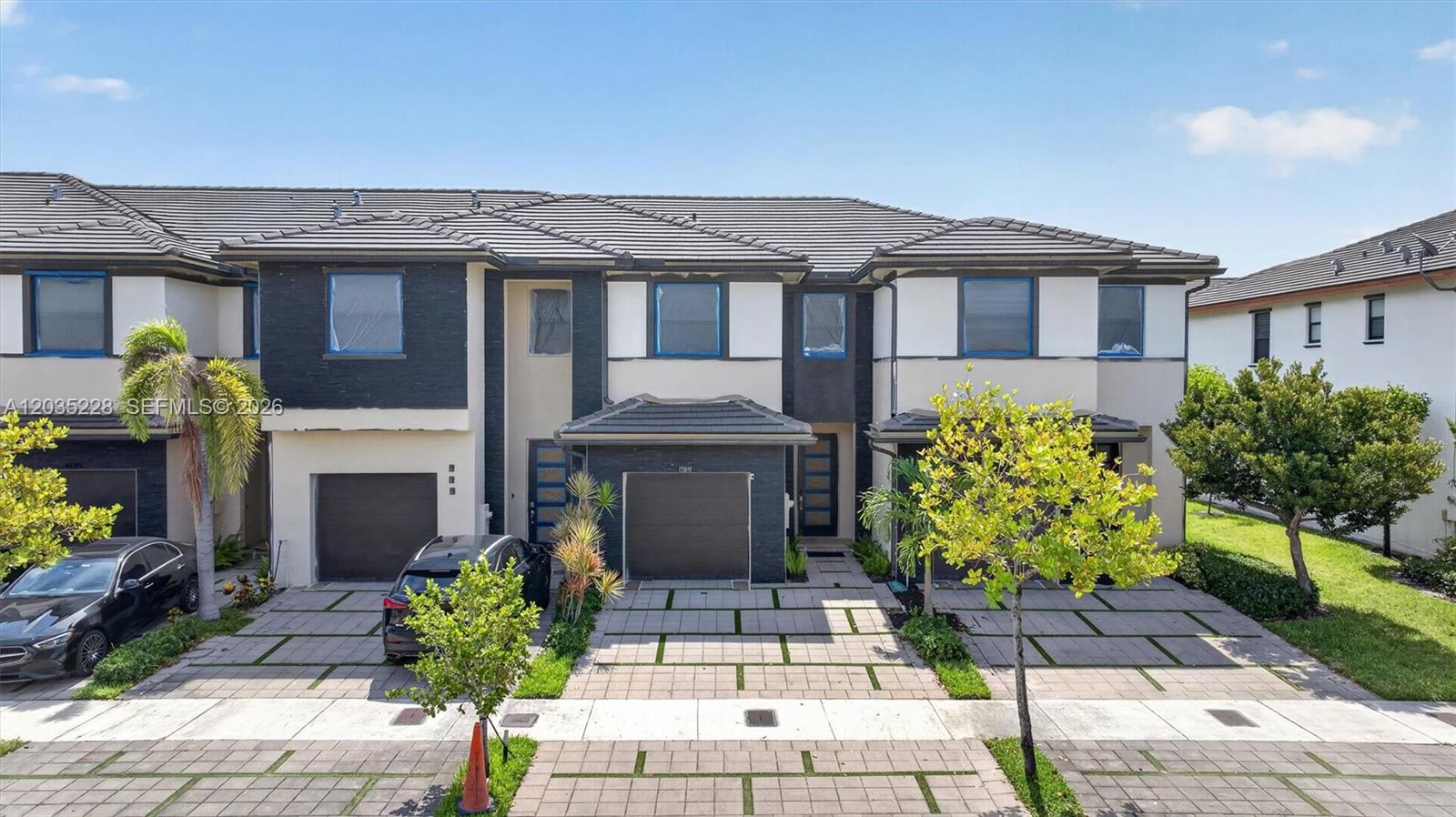 A multi-unit residential building features dark stone accents, gray tiled roofs, and paved driveways — 15841 NW 91st Ct, Miami Lakes FL 33018, MIAMI LAKES, FL