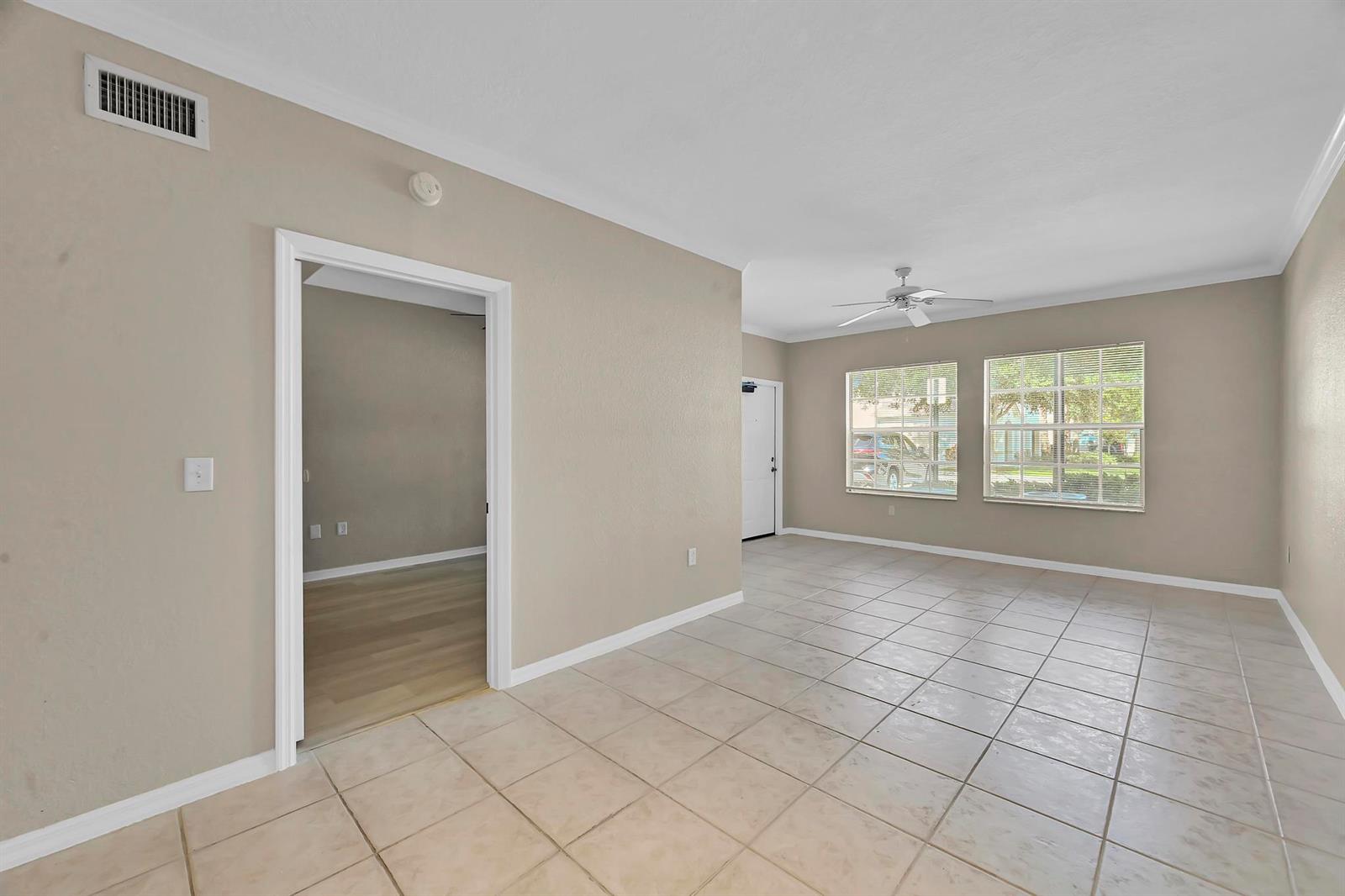 A living room with beige walls, tile flooring, a ceiling fan, and a doorway to another room — 196 SE Kitching Circle, Stuart FL 34994, STUART, FL