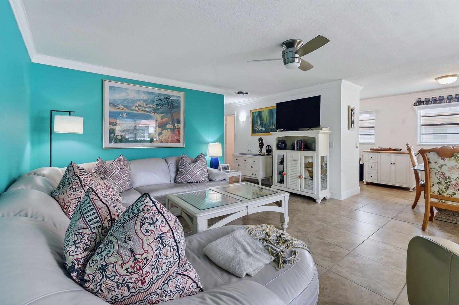 A living room features a turquoise accent wall, a white sectional sofa, and tile flooring — 1225 NW 21st Street # 314, Stuart FL 34994, STUART, FL