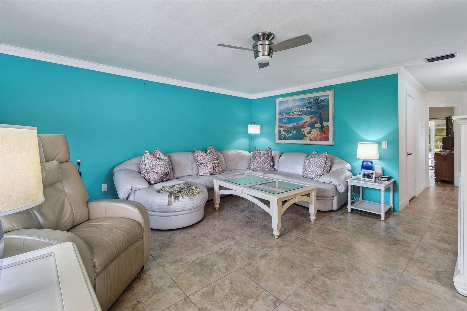 A living room features turquoise walls, a large white sectional sofa, and tile flooring — 1225 NW 21st Street # 314, Stuart FL 34994, STUART, FL