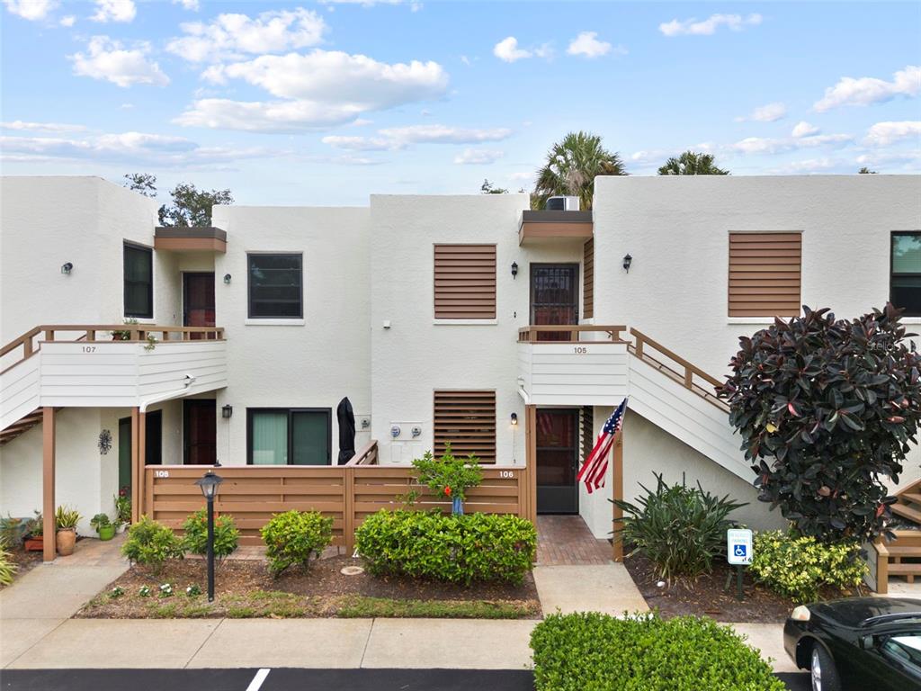 Exterior view of a two-story apartment building with balconies, stairs, and ground-level patios — 106 TIDEWATER DRIVE, BRADENTON, FL