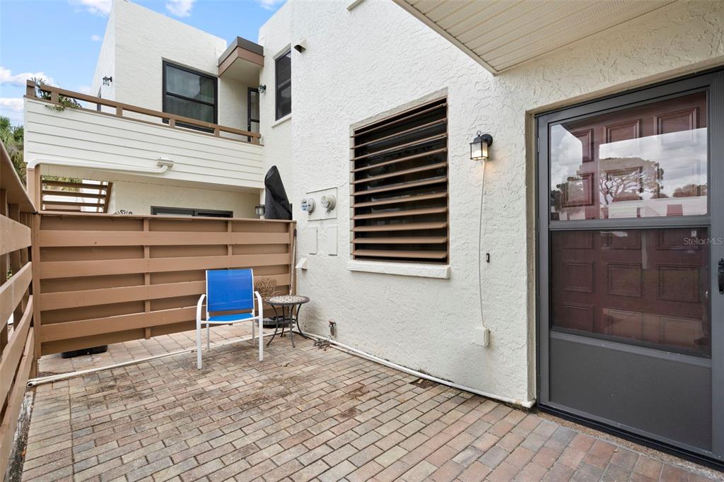 A brick patio features a blue chair, a small table, and a wooden privacy fence — 106 TIDEWATER DRIVE, BRADENTON, FL