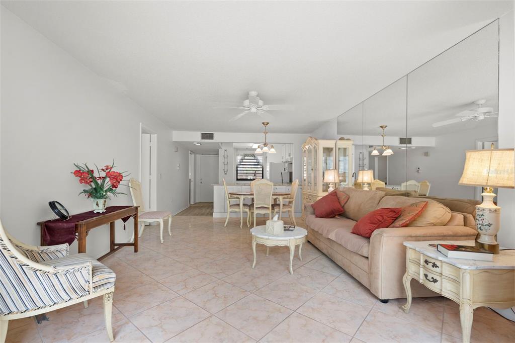 A living room with tile floors, a beige sofa, and a mirrored wall — 106 TIDEWATER DRIVE, BRADENTON, FL