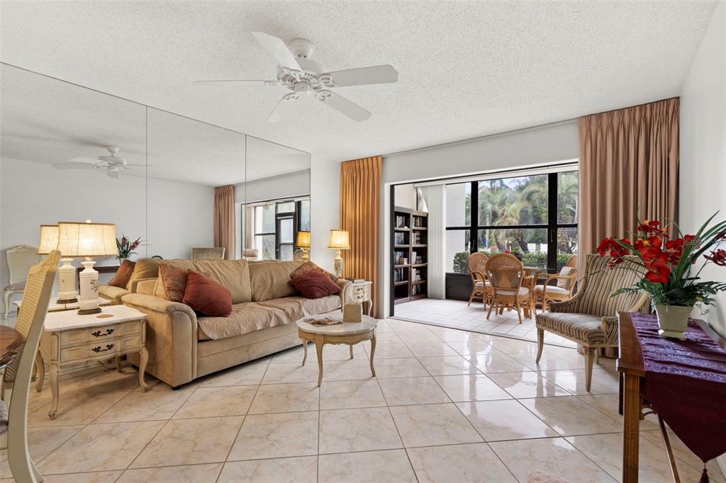 A living room features a beige sofa, tiled floors, mirrored walls, and a sliding glass door — 106 TIDEWATER DRIVE, BRADENTON, FL