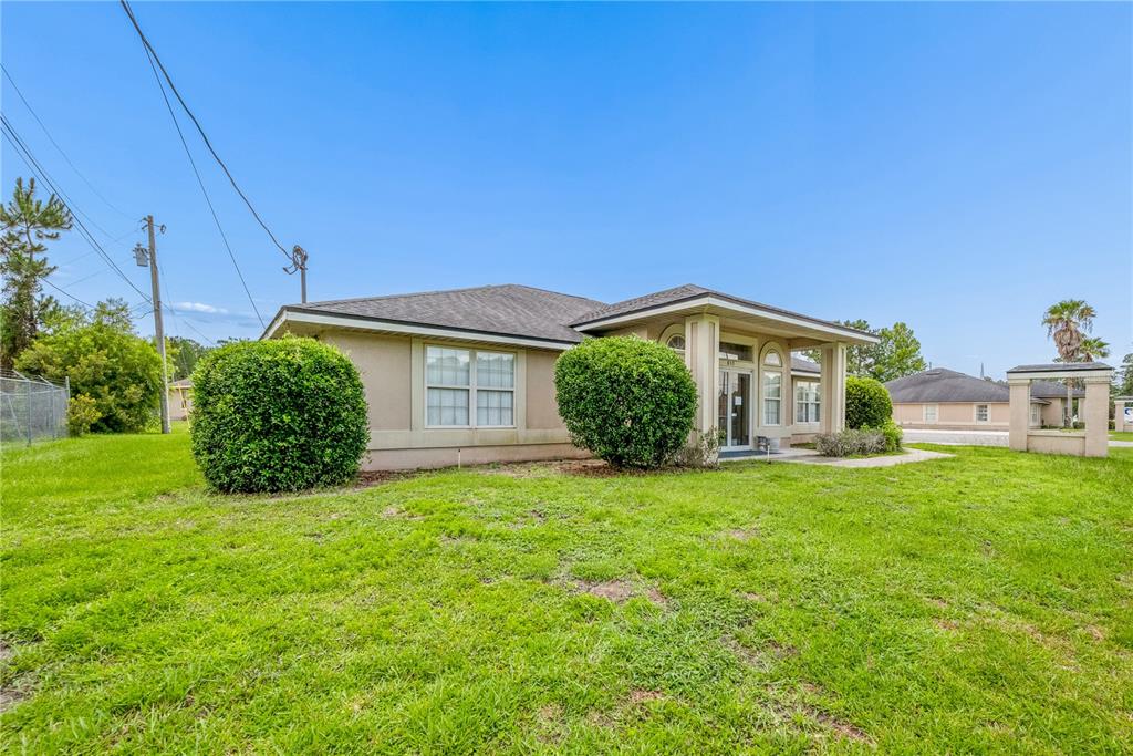 A tan, single-story building with a covered entrance and two large bushes in the yard — 853 SW SISTERS WELCOME ROAD, LAKE CITY, FL