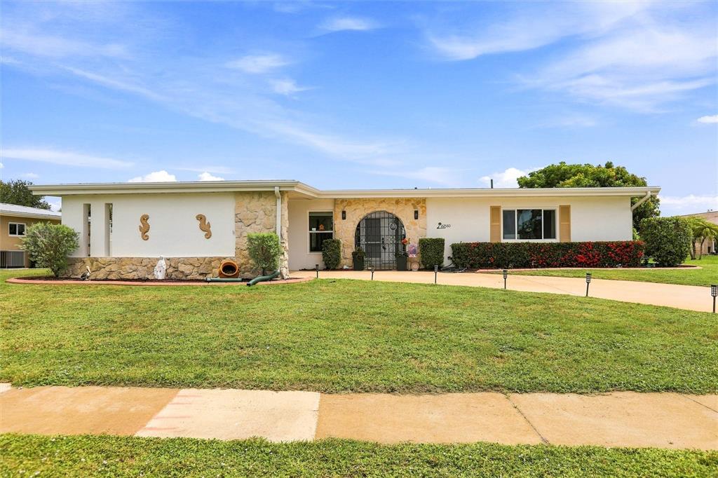 A single-story house features a white facade, stone accents, and a curved front entryway — 22580 BOLANOS COURT, PORT CHARLOTTE, FL