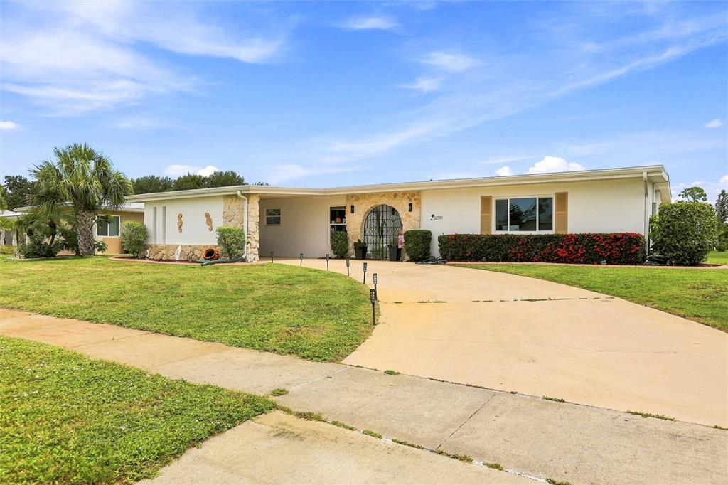 A single-story house with a stone-accented entryway, a curved driveway, and a manicured lawn — 22580 BOLANOS COURT, PORT CHARLOTTE, FL