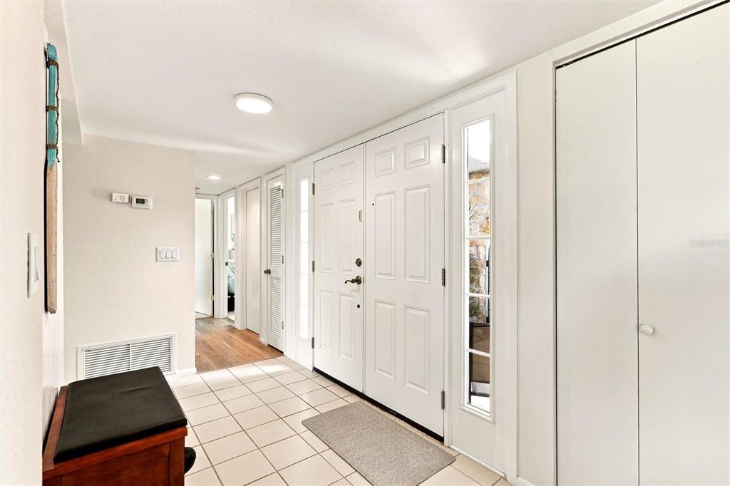 An entryway features white double doors, tiled flooring, a wooden bench, and a hallway — 22580 BOLANOS COURT, PORT CHARLOTTE, FL
