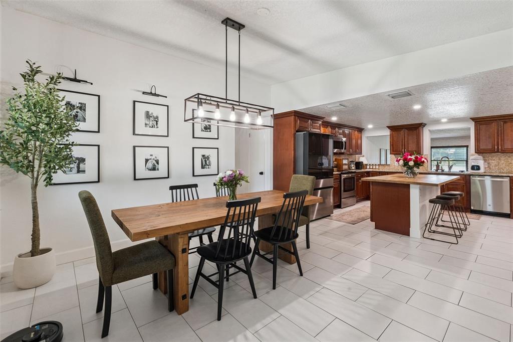 A dining area with a wooden table and black chairs sits adjacent to a kitchen — 4533 STILWELL DRIVE, ORLANDO, FL