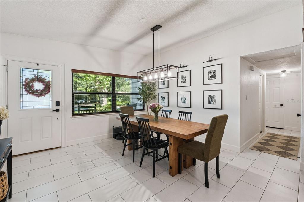A dining room features a wooden table, black chairs, a rectangular chandelier, and white tile — 4533 STILWELL DRIVE, ORLANDO, FL