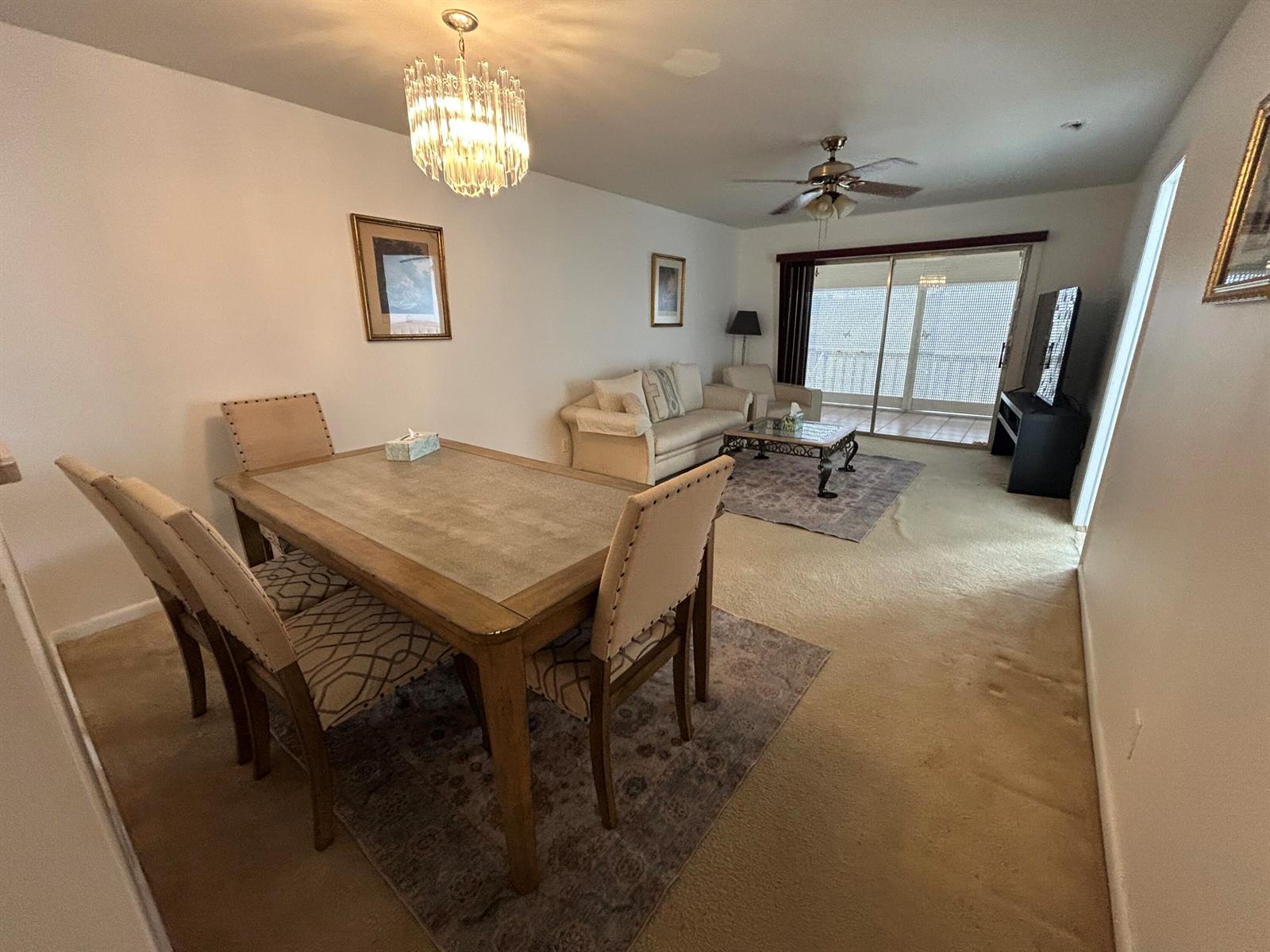 A dining area with a chandelier and a living room with a balcony view — 6600 Royal Palm Boulevard # 304b, Margate FL 33063, MARGATE, FL