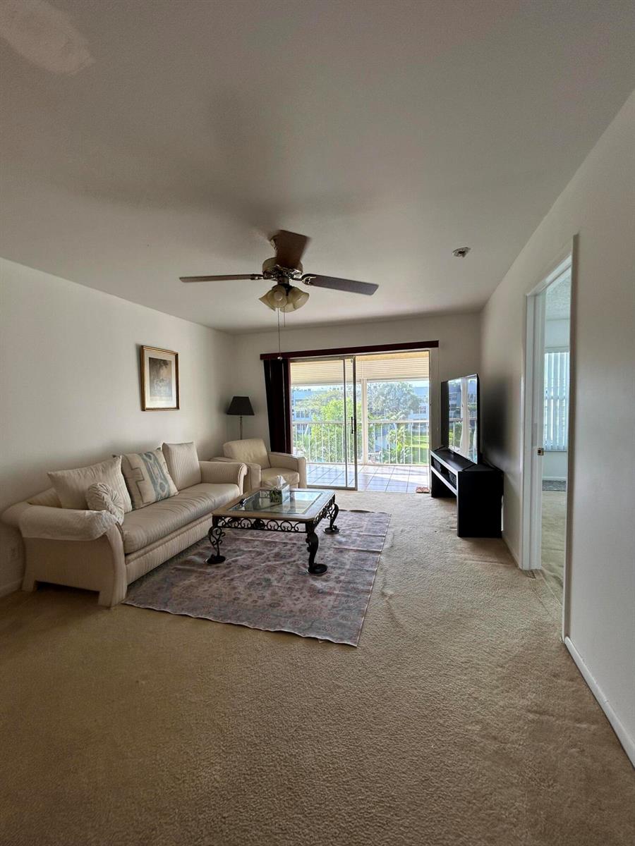 A living room features beige carpet, a sofa, a coffee table, and a sliding glass door — 6600 Royal Palm Boulevard # 304b, Margate FL 33063, MARGATE, FL