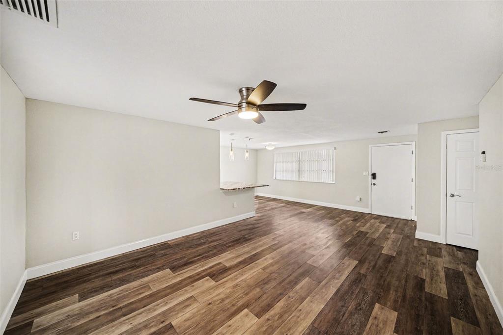An open-concept living area features wood-look flooring, a ceiling fan, and a kitchen breakfast bar — 7541 SPIREA DRIVE, PORT RICHEY, FL