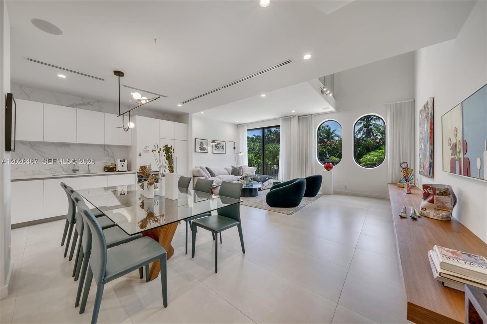 A modern open-concept living and dining area features white cabinetry, a glass table, and arched windows — 10659 NE Quaybridge Ct # C5, Miami FL 33138, MIAMI, FL
