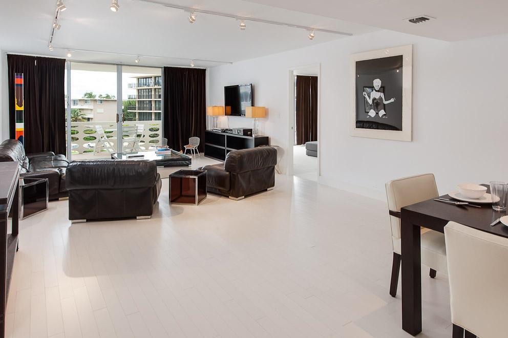 A bright living and dining area with white floors, dark leather furniture, and a balcony — 100 Sunrise Avenue # 404, Palm Beach FL 33480, PALM BEACH, FL