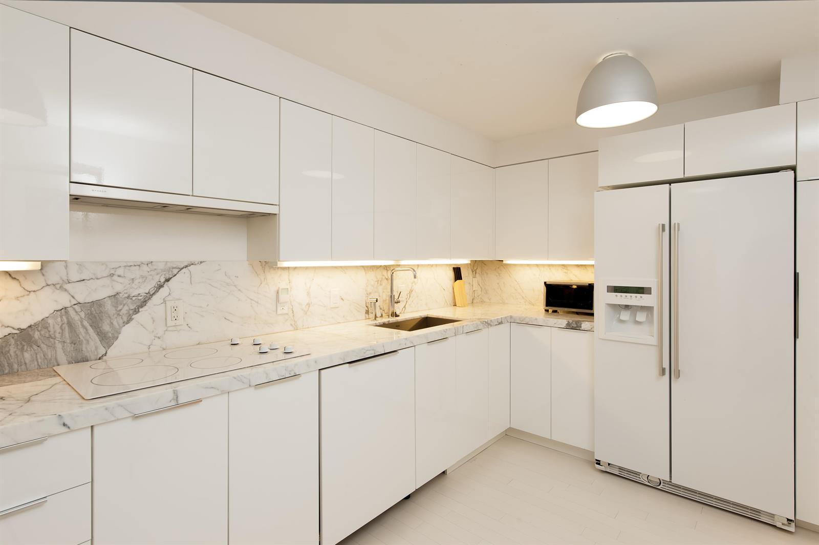 A modern kitchen features white cabinets, marble countertops, a marble backsplash, and stainless steel appliances — 100 Sunrise Avenue # 404, Palm Beach FL 33480, PALM BEACH, FL