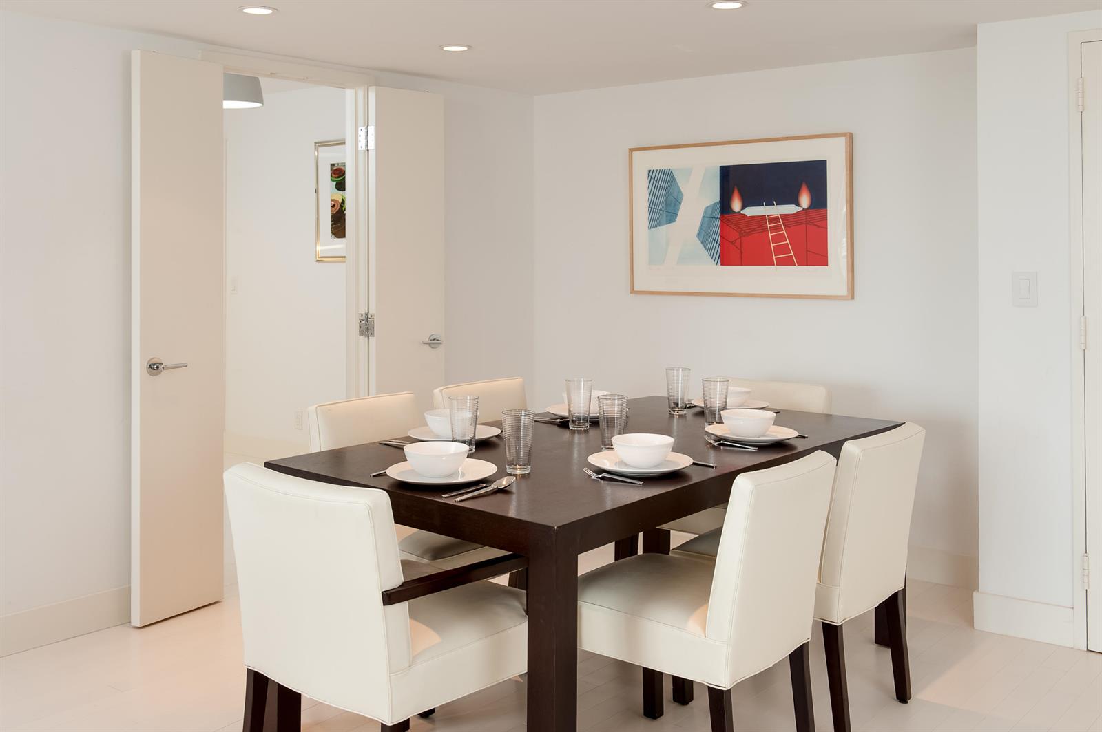 A dining room features a dark wood table, white chairs, and framed artwork on white walls — 100 Sunrise Avenue # 404, Palm Beach FL 33480, PALM BEACH, FL