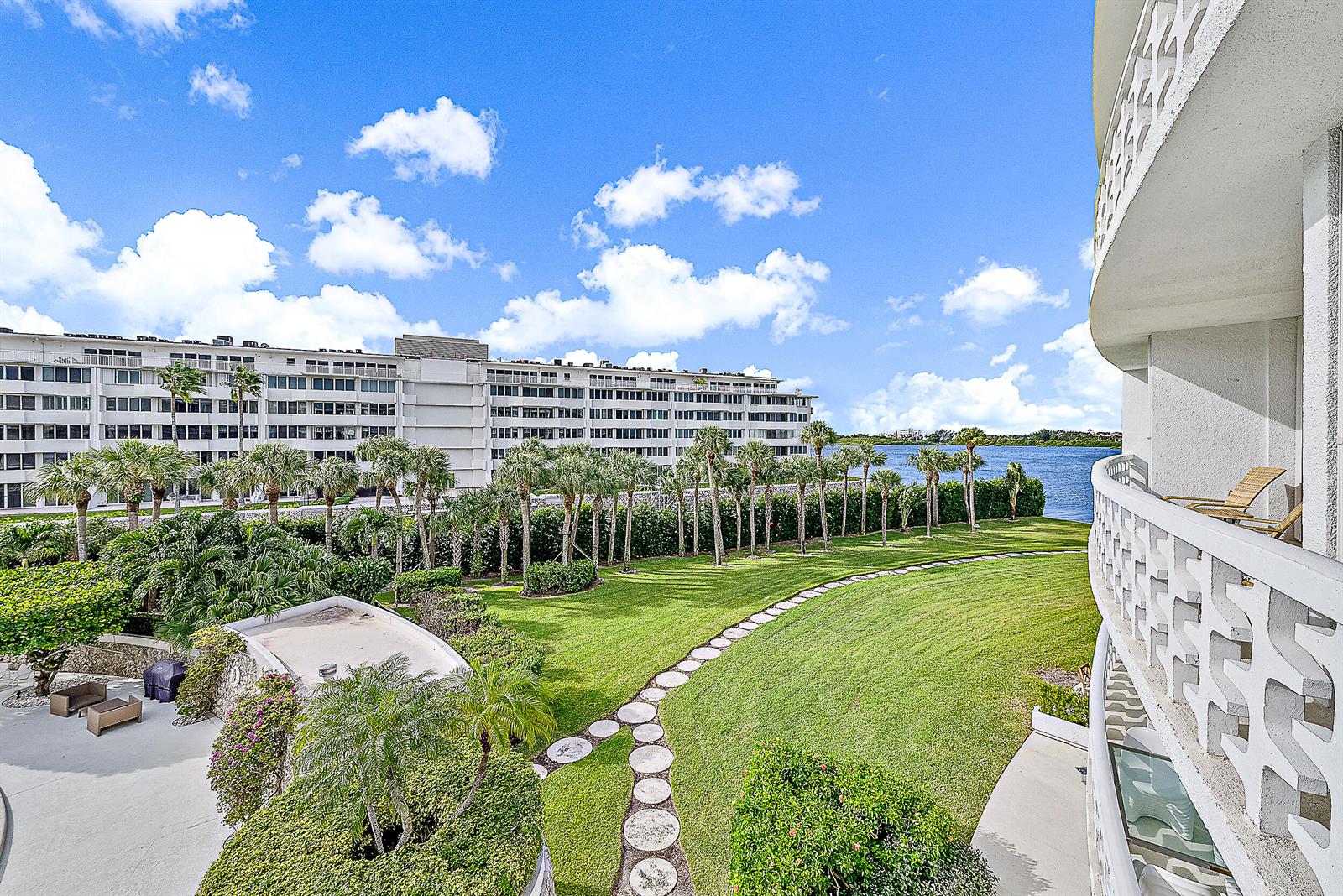 A view from a balcony overlooking a grassy lawn, palm trees, and a body of water — 2760 S Ocean Boulevard # 310, Palm Beach FL 33480, PALM BEACH, FL