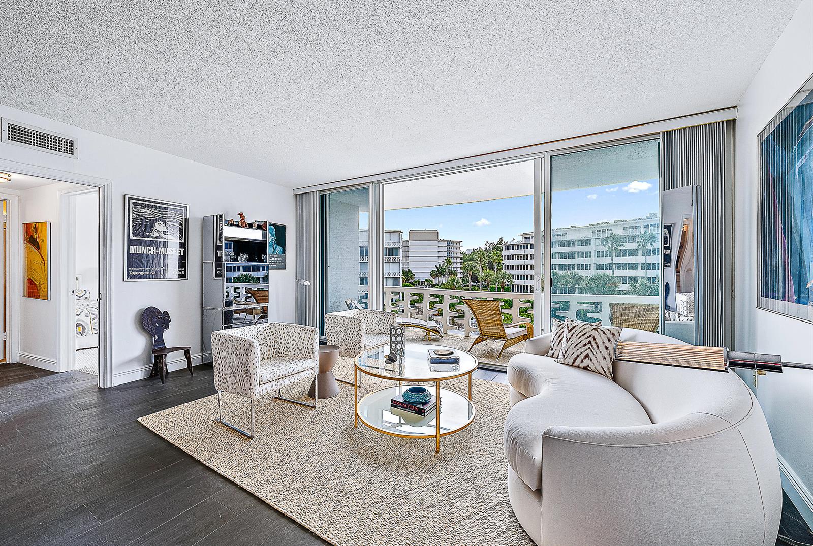 A living room features a curved sofa, glass coffee table, and sliding doors to a balcony — 2760 S Ocean Boulevard # 310, Palm Beach FL 33480, PALM BEACH, FL