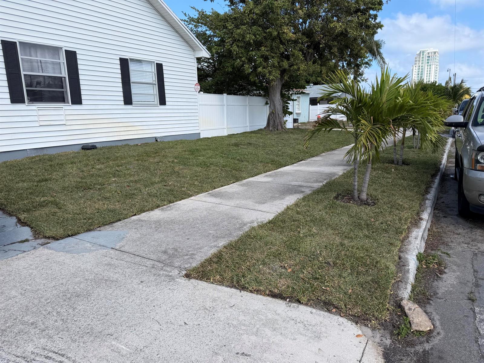 A white house with black shutters sits next to a sidewalk and a palm tree — 631 46th Street, West Palm Beach FL 33407, WEST PALM BEACH, FL