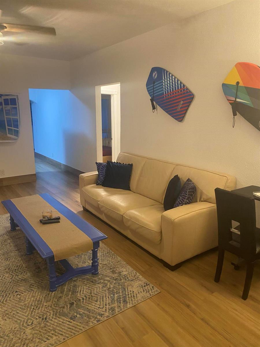A living room features a beige sofa, a blue coffee table, and two wall-mounted boogie boards — 631 46th Street, West Palm Beach FL 33407, WEST PALM BEACH, FL