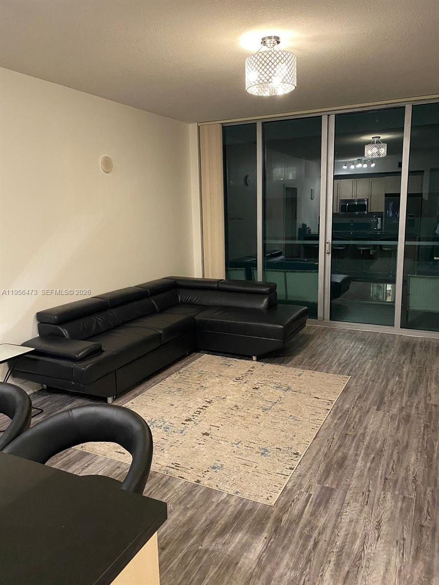 A living room features a black leather sectional sofa, a patterned rug, and sliding glass doors — 1111 SW 1st Ave, Miami FL 33130, MIAMI, FL