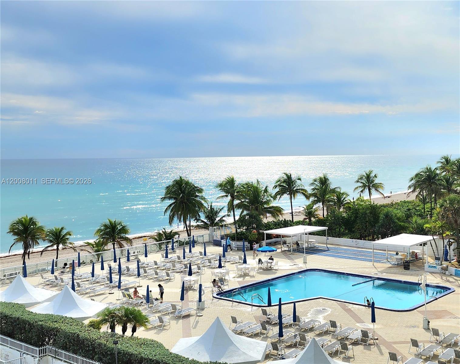 An elevated view shows a swimming pool deck with lounge chairs and palm trees by the ocean — 2030 S Ocean Dr # 2026, Hallandale Beach FL 33009, HALLANDALE BEACH, FL