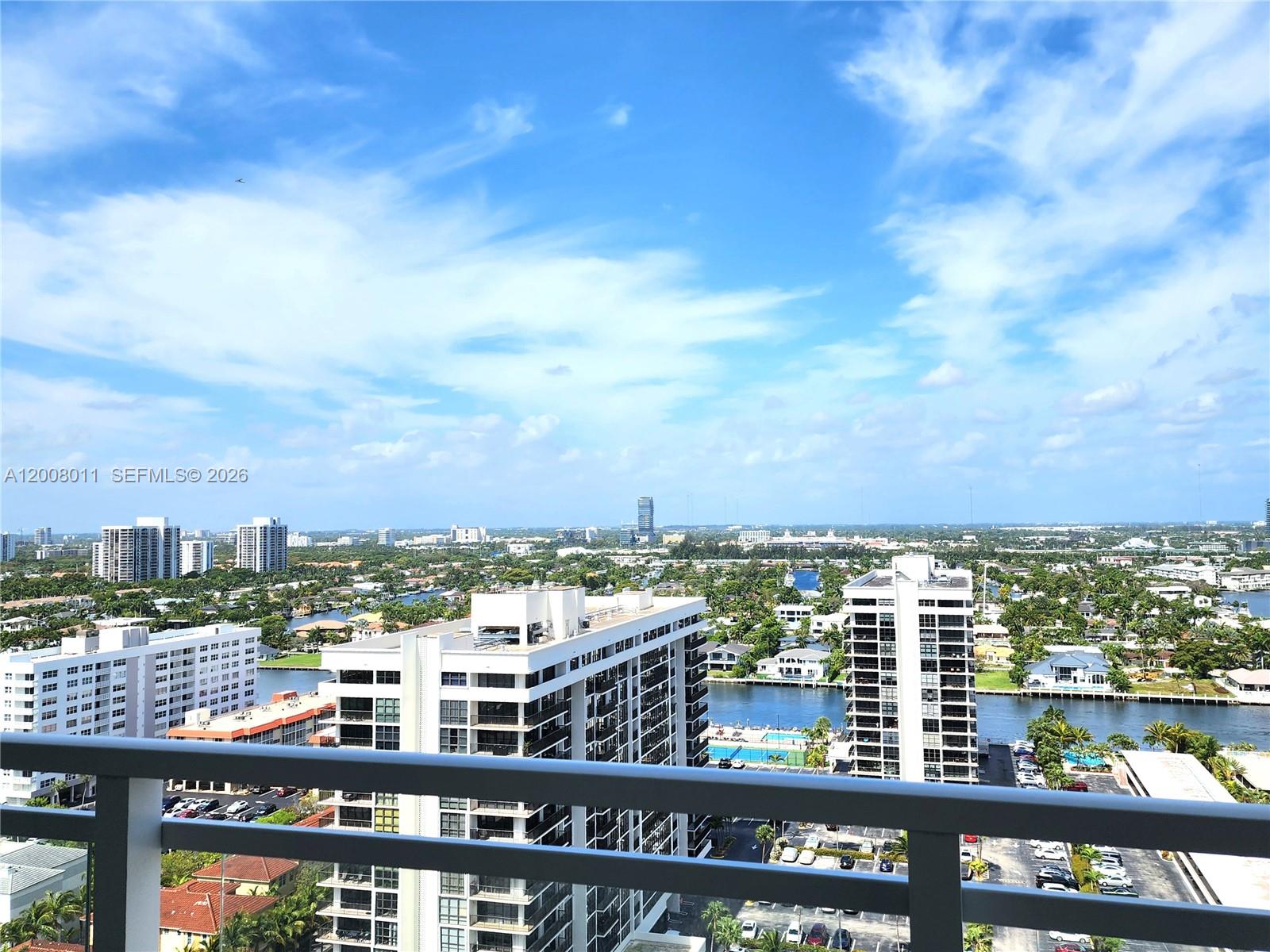 An elevated view from a balcony overlooks residential buildings, a waterway, and a distant skyline — 2030 S Ocean Dr # 2026, Hallandale Beach FL 33009, HALLANDALE BEACH, FL