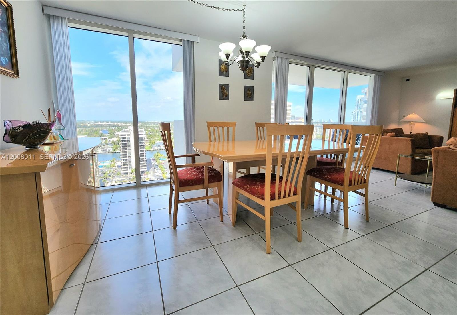 A dining area features a wooden table with six chairs, tile flooring, and floor-to-ceiling windows — 2030 S Ocean Dr # 2026, Hallandale Beach FL 33009, HALLANDALE BEACH, FL