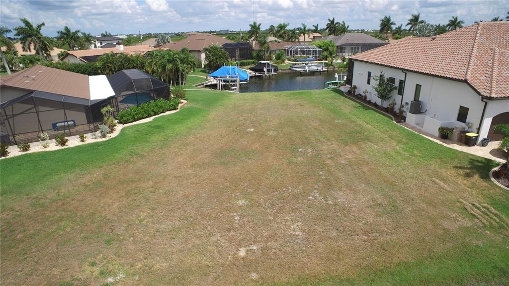 An aerial view shows a vacant grassy lot situated between two houses near a canal — 760 ANTALYA COURT, PUNTA GORDA, FL