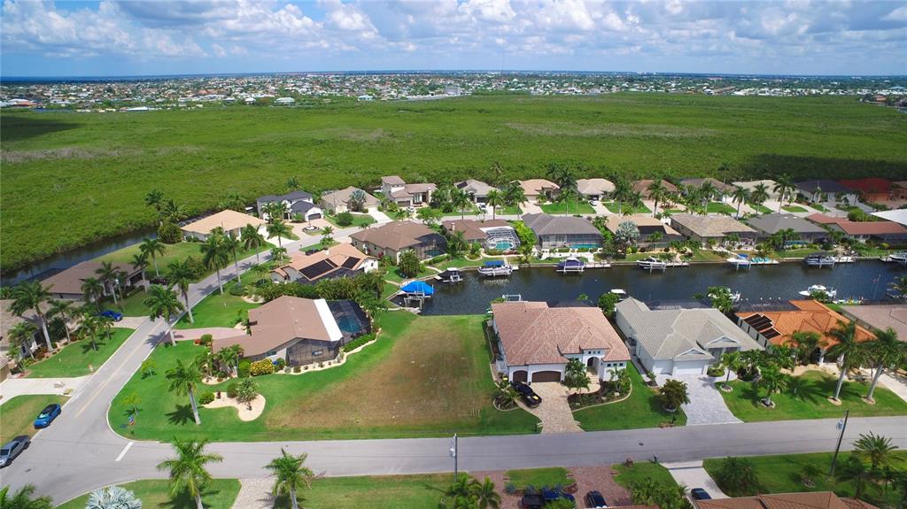 An aerial view shows a vacant residential lot situated between two houses along a canal — 760 ANTALYA COURT, PUNTA GORDA, FL