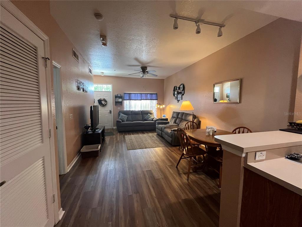 A living room and dining area feature wood-look flooring, neutral walls, and a ceiling fan — 2610 LODI CIRCLE UNIT 103, KISSIMMEE, FL