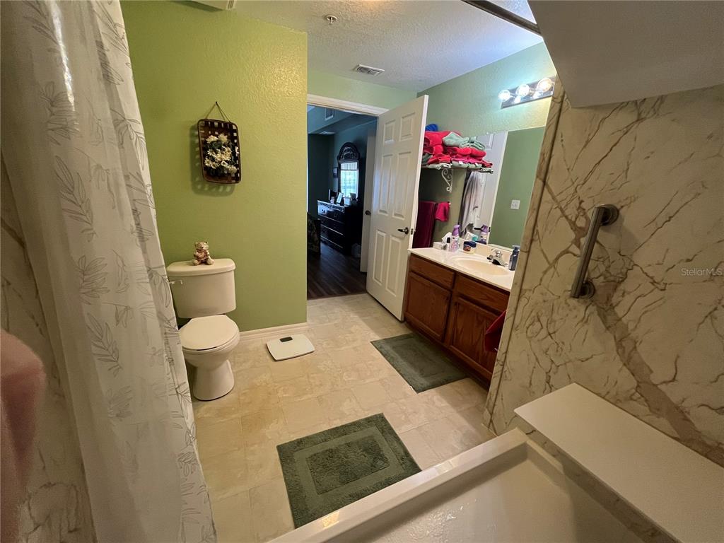 A bathroom features a toilet, a vanity with a sink, and a tiled shower area — 2610 LODI CIRCLE UNIT 103, KISSIMMEE, FL