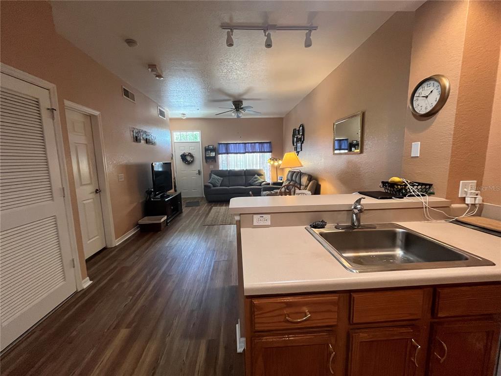 A kitchen sink and counter overlook a living room with wood-look flooring and a sofa — 2610 LODI CIRCLE UNIT 103, KISSIMMEE, FL