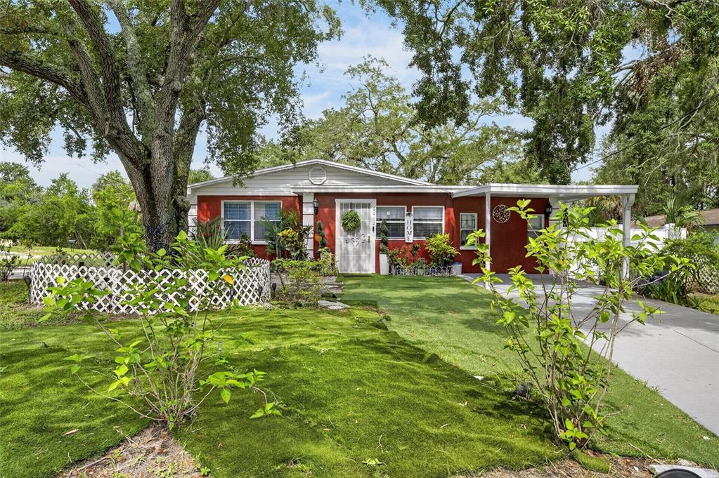 A red single-story house with a white front door, carport, and green lawn — 6402 N 41ST STREET, TAMPA, FL