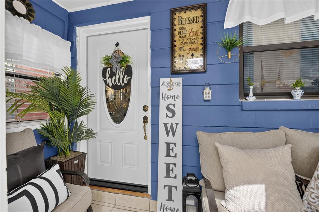 A covered porch features blue siding, a white front door, seating, and decorative wall signs — 6402 N 41ST STREET, TAMPA, FL