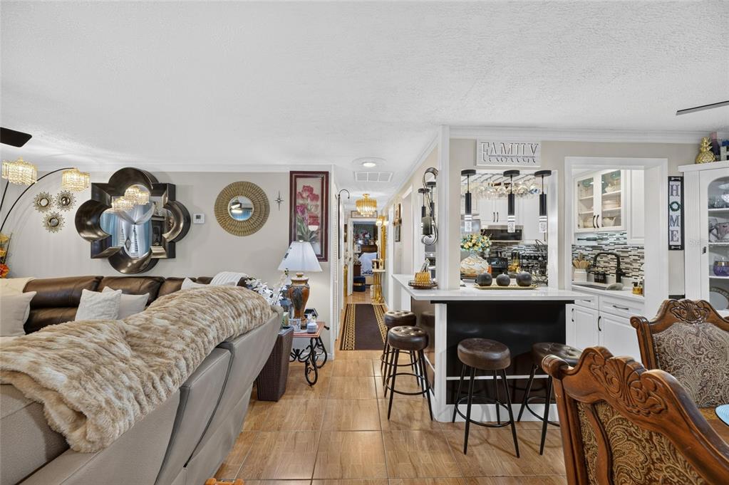 A living room with a brown leather sofa, breakfast bar, and tiled flooring — 6402 N 41ST STREET, TAMPA, FL