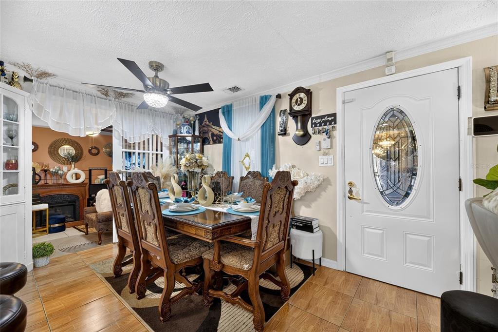 A dining room features a wooden table with six chairs, tile flooring, and a front door — 6402 N 41ST STREET, TAMPA, FL