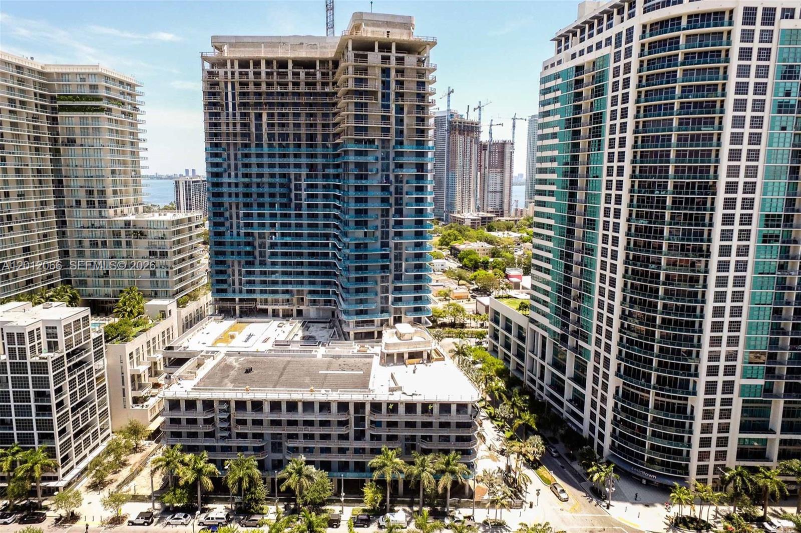 An aerial view shows a tall, partially constructed residential building surrounded by finished high-rise towers — 3470 E Coast Ave # H0302, Miami FL 33137, MIAMI, FL