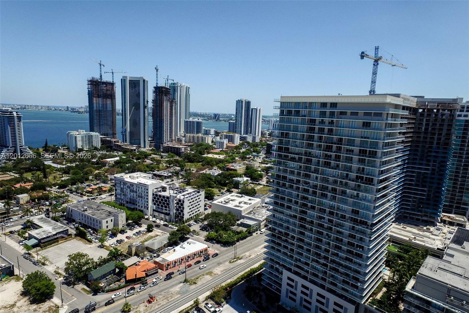 An aerial view of a city skyline featuring high-rise buildings, construction cranes, and a bay — 3470 E Coast Ave # H0302, Miami FL 33137, MIAMI, FL