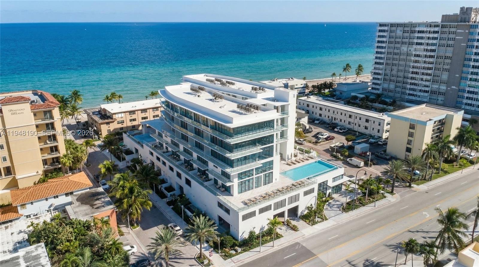 An aerial view shows a modern white multi-story beachfront building with a rooftop pool — 3319 N Ocean drive, Hollywood FL 33019, HOLLYWOOD, FL