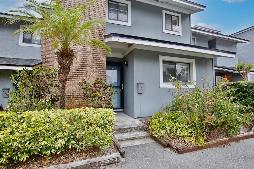 A two-story gray townhouse with a brick chimney, a palm tree, and landscaping — 713 SAINT MATTHEW CIRCLE, ALTAMONTE SPRINGS, FL