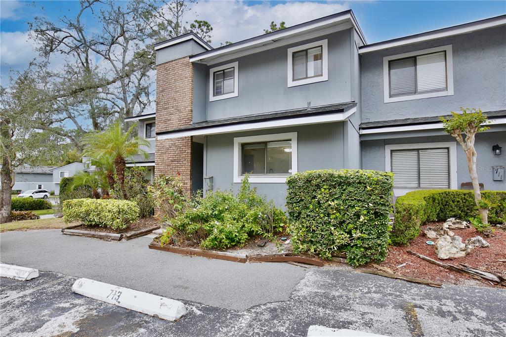A two-story gray townhouse exterior features a brick chimney, landscaping, and a parking space — 713 SAINT MATTHEW CIRCLE, ALTAMONTE SPRINGS, FL