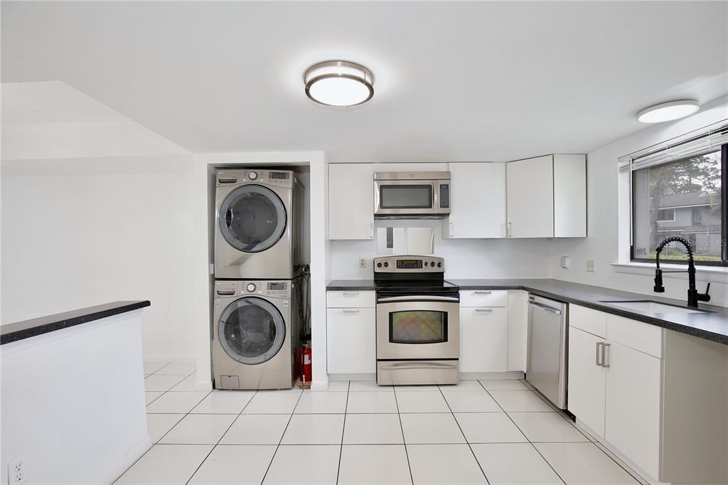 A kitchen with white cabinets, stainless steel appliances, a stacked washer and dryer, and tile flooring — 713 SAINT MATTHEW CIRCLE, ALTAMONTE SPRINGS, FL
