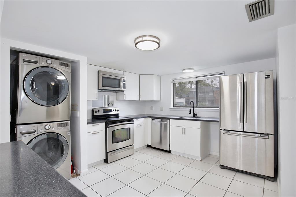A kitchen with white cabinets, stainless steel appliances, a stacked washer-dryer, and white tile flooring — 713 SAINT MATTHEW CIRCLE, ALTAMONTE SPRINGS, FL