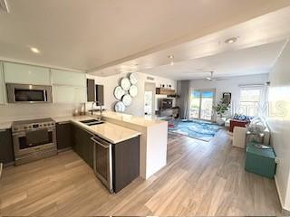 A modern kitchen with dark cabinetry and stainless steel appliances opens into a living area — 1 PALMAS DORADAS UNIT 513, HUMACAO, PR