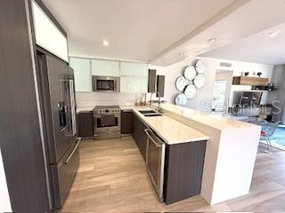 A modern kitchen features dark cabinetry, stainless steel appliances, and a white quartz breakfast bar — 1 PALMAS DORADAS UNIT 513, HUMACAO, PR