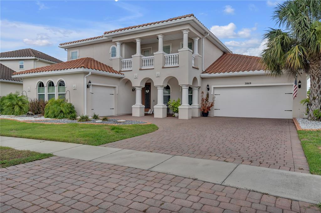A two-story stucco house features a tile roof, arched entry, and a paved driveway — 3869 SHORESIDE DRIVE, KISSIMMEE, FL